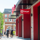 Shoppers walk past the front of a small Target store.